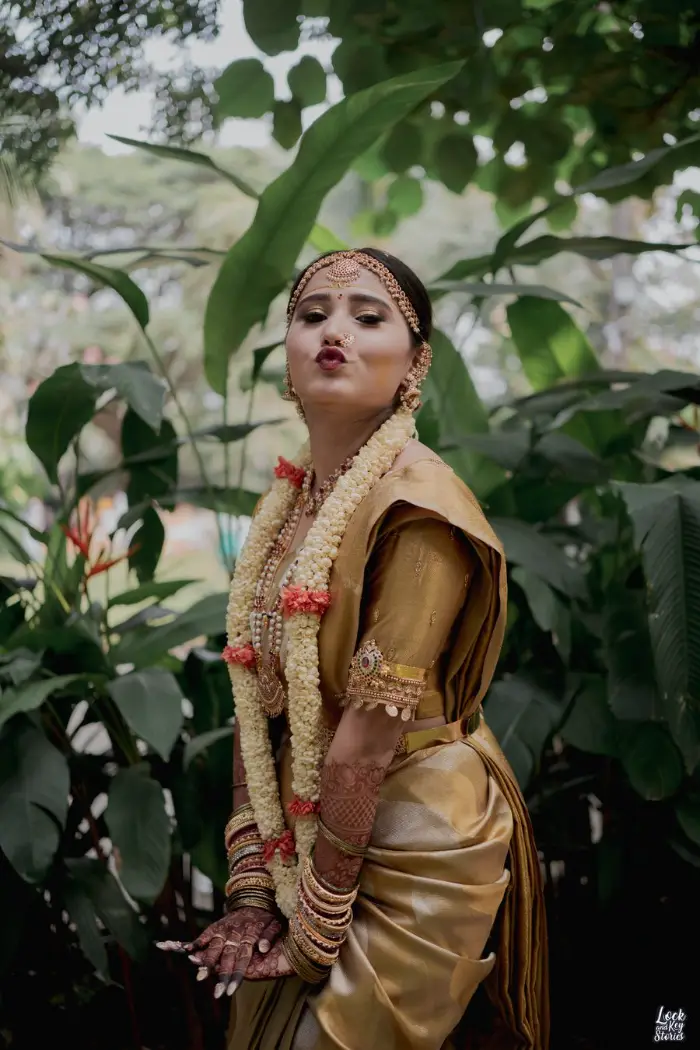 Bride in a gold Kanjeevaram-style bridal silk saree with temple jewellery and jasmine garlands