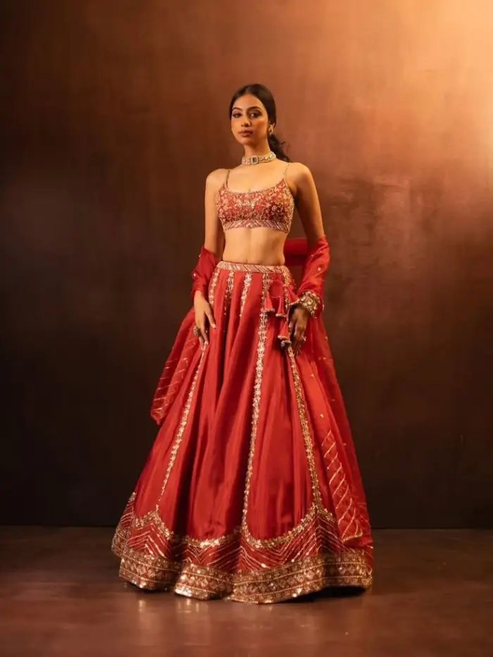Model wearing a red and gold embroidered bridal lehenga with dupatta